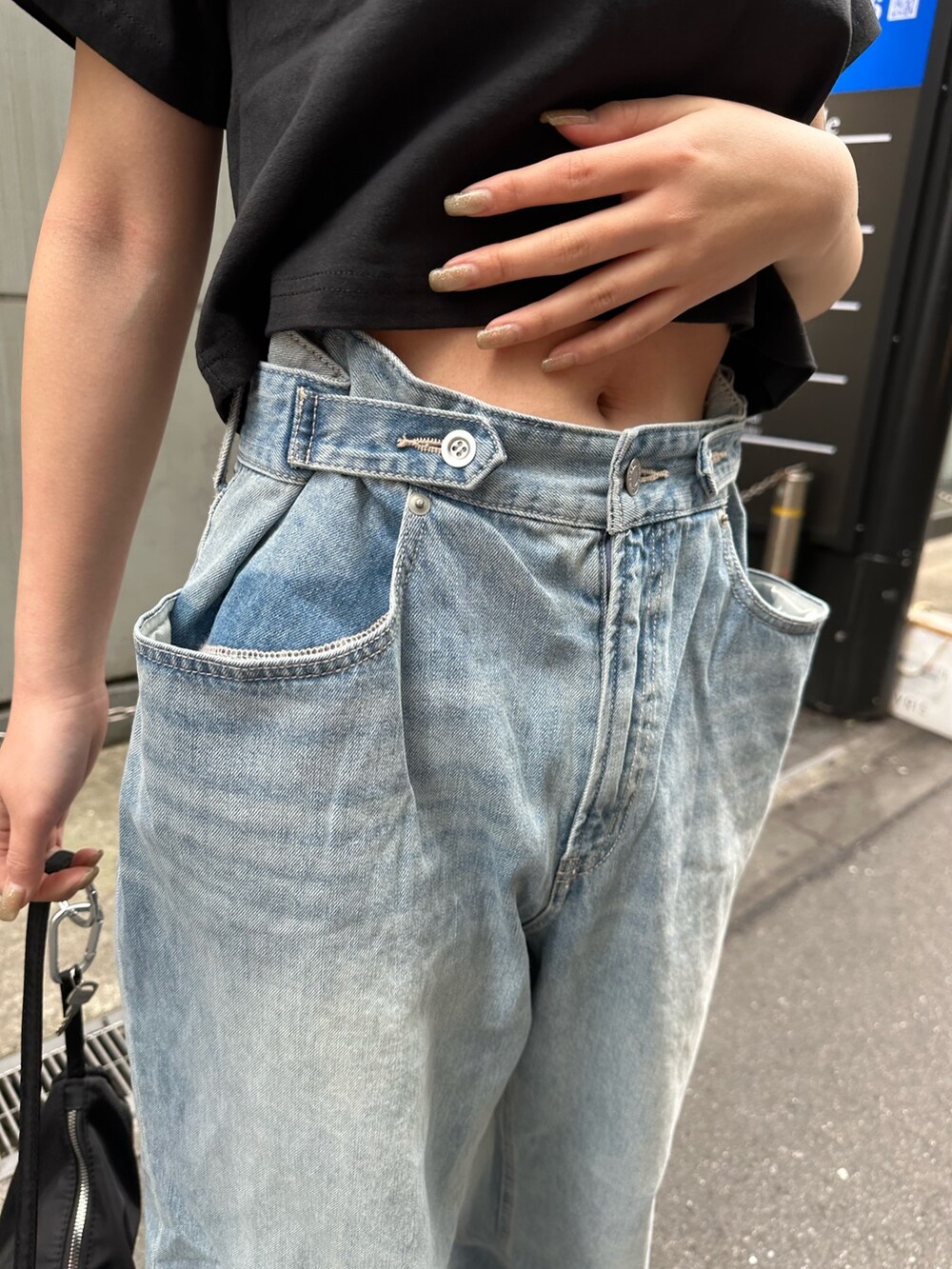 ブラック系のTシャツ/カットソー、ブラック系のスニーカー、ブルー系のデニムパンツを着用したレディースの春コーディネートの7枚目の写真