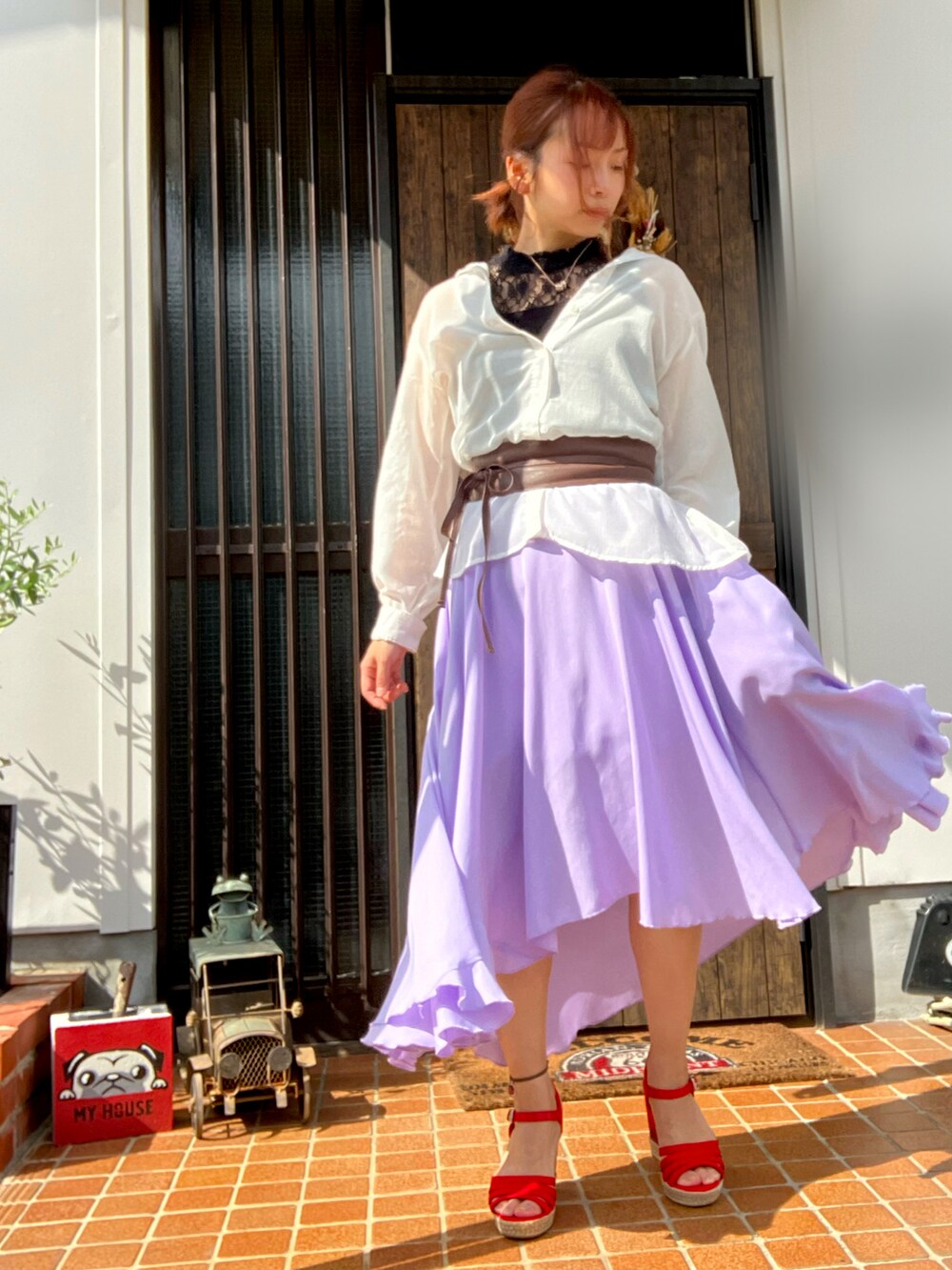 パープル系のスカート、レッド系のサンダルを着用したレディースの秋コーディネートの3枚目の写真