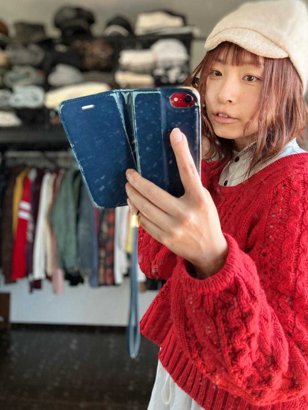 レッド系のニット/セーター、ホワイト系のワンピース、ベージュ系のキャスケットを着用したレディースの冬コーディネートの3枚目の写真