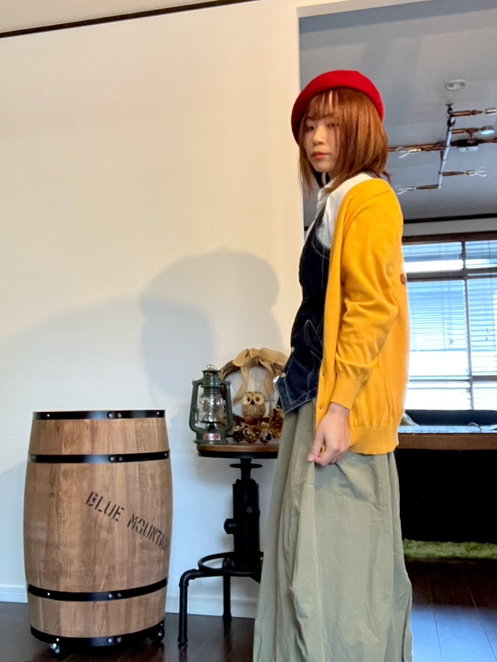 イエロー系のカーディガン/ボレロ、グリーン系のスカート、ブルー系のベストを着用したレディースの秋コーディネートの5枚目の写真