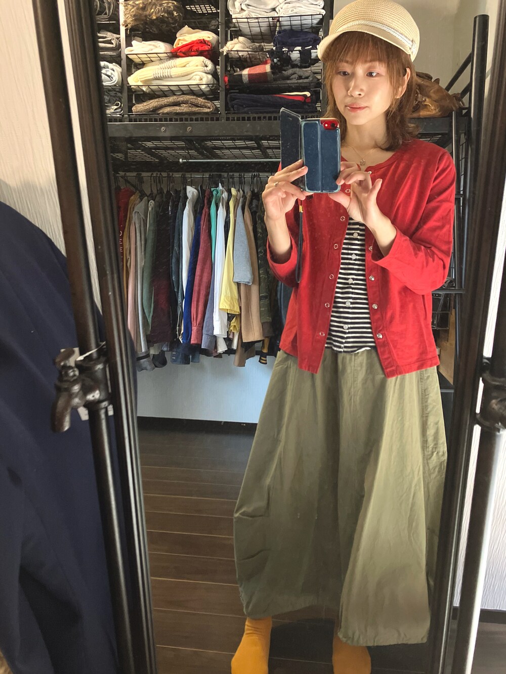 グリーン系のスカート、レッド系のカーディガン/ボレロ、ベージュ系のキャスケットを着用したレディースの春コーディネートの2枚目の写真