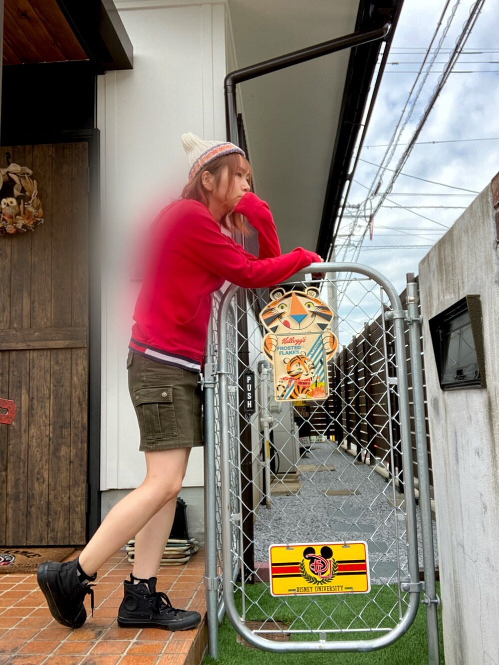 グリーン系のスカート、レッド系のパーカー、ブラック系のスニーカーを着用したレディースの秋コーディネートの2枚目の写真