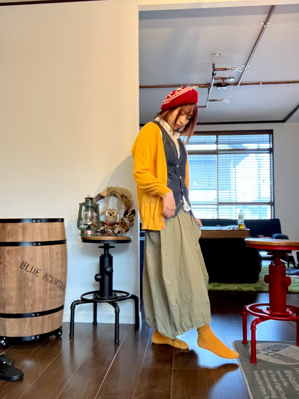 イエロー系のカーディガン/ボレロ、グリーン系のスカート、ブルー系のベストを着用したレディースの秋コーディネートの2枚目の写真