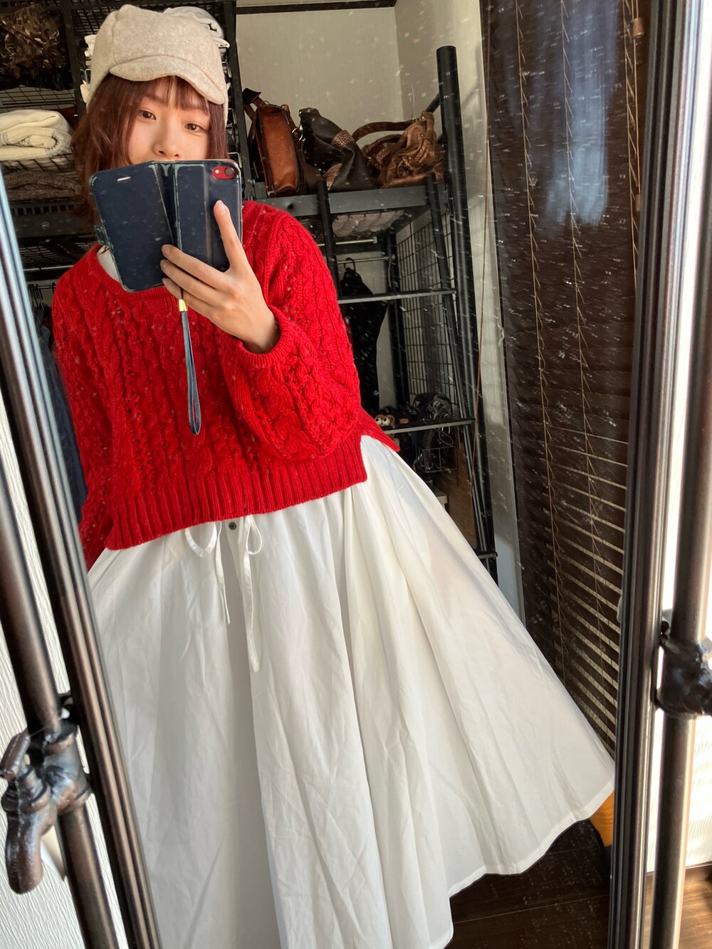 レッド系のニット/セーター、ホワイト系のワンピース、ベージュ系のキャスケットを着用したレディースの冬コーディネートの2枚目の写真