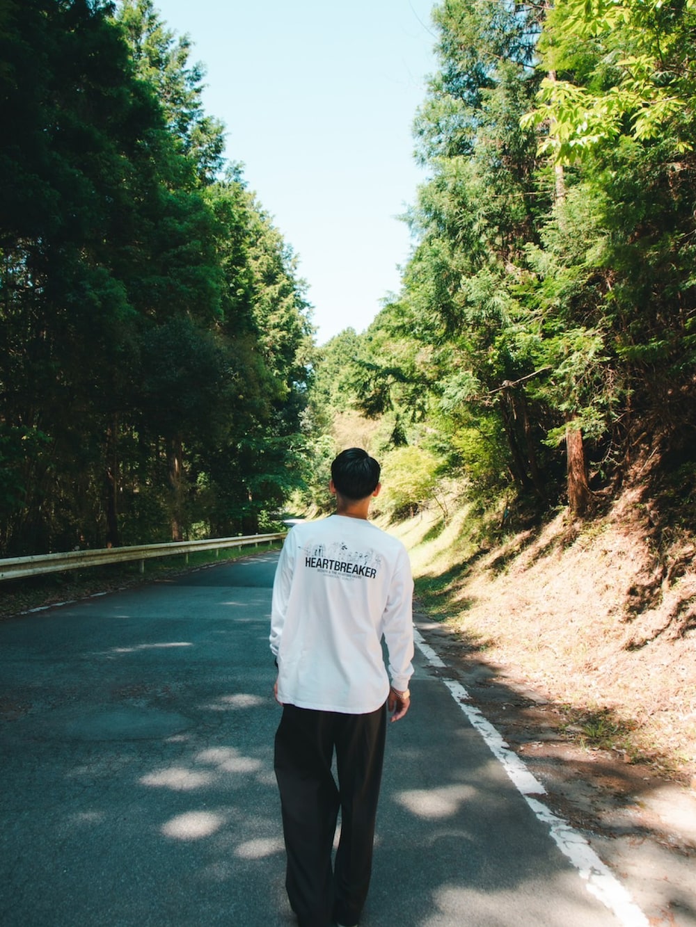 ホワイト系のTシャツ/カットソー、ブラウン系のスラックス、ブラック系のスニーカーを着用したメンズの秋コーディネートの2枚目の写真