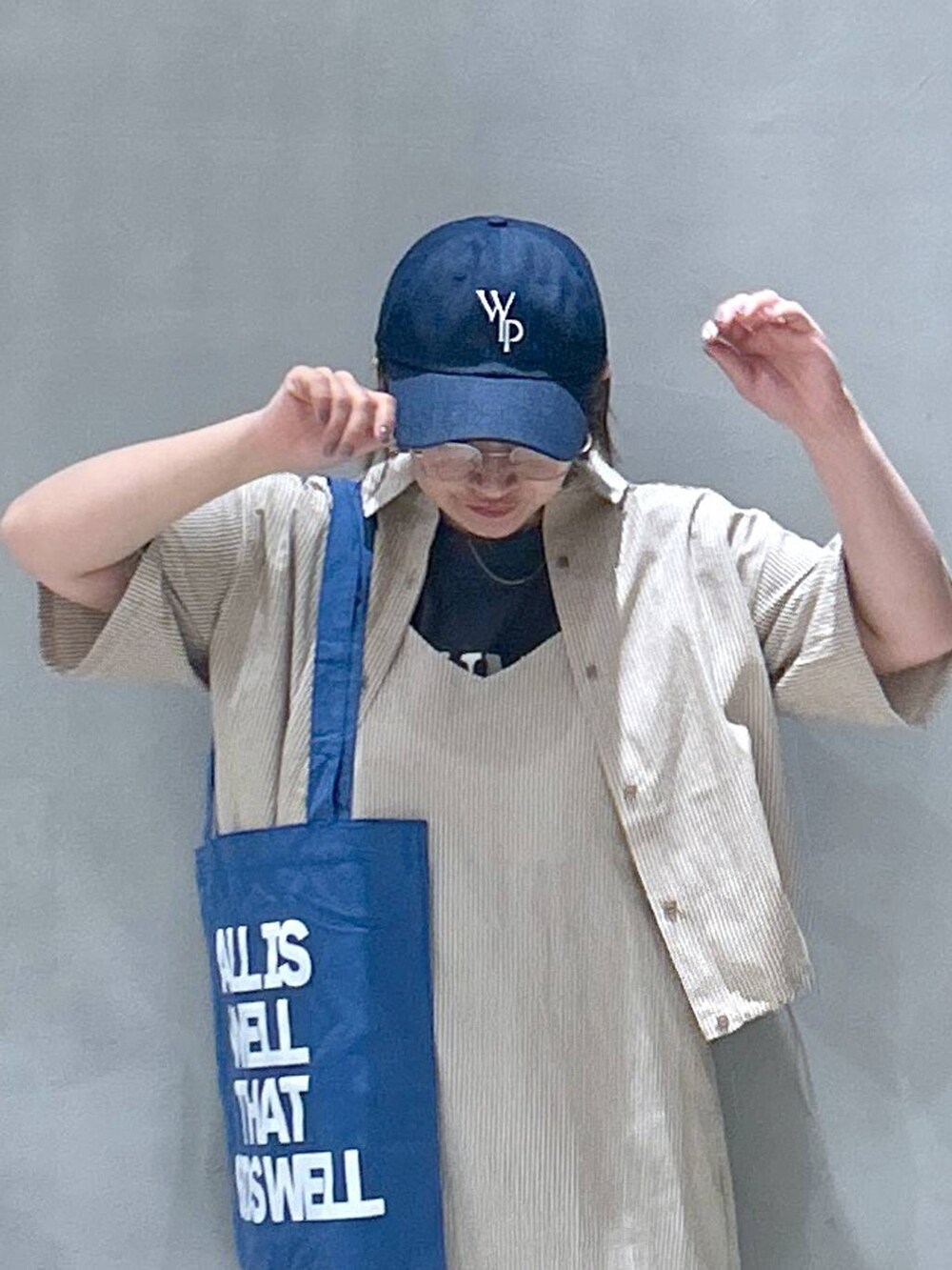 グレー系のスニーカー、ブルー系のトートバッグ、グレー系のTシャツ/カットソーを着用したレディースの春コーディネートの3枚目の写真