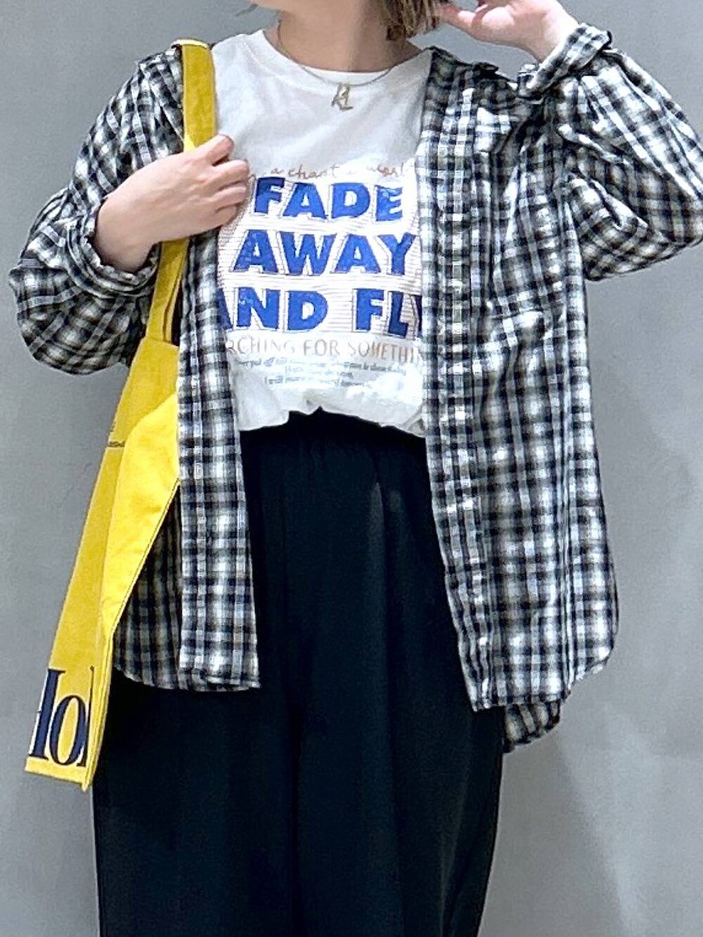 ブラック系のその他パンツ、ブラック系のシャツ/ブラウス、イエロー系のトートバッグを着用したレディースの春コーディネートの3枚目の写真