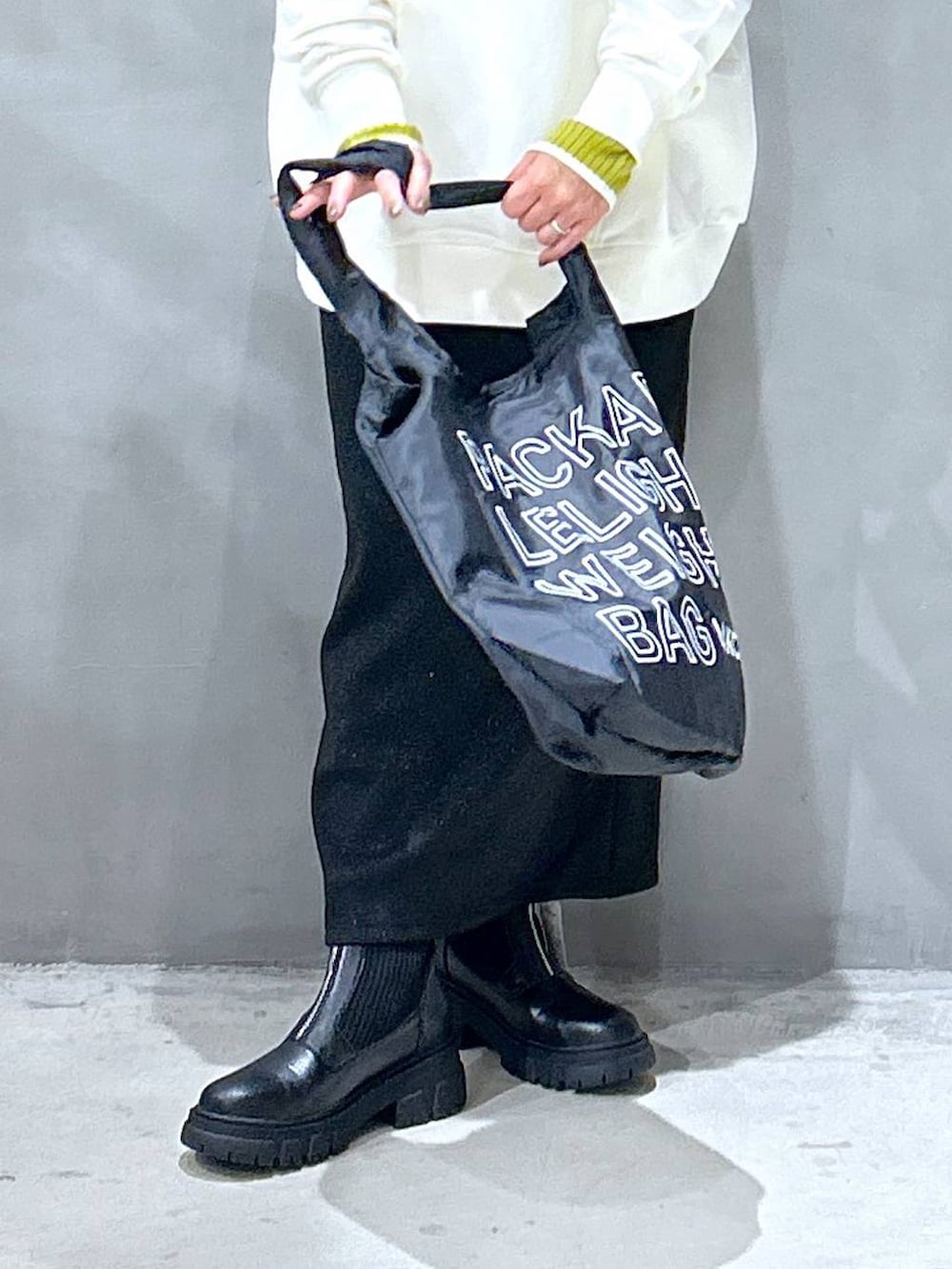 グリーン系のニット/セーター、ブラック系のブーツ、ブラック系のエコバッグ/サブバッグを着用したレディースの冬コーディネートの4枚目の写真