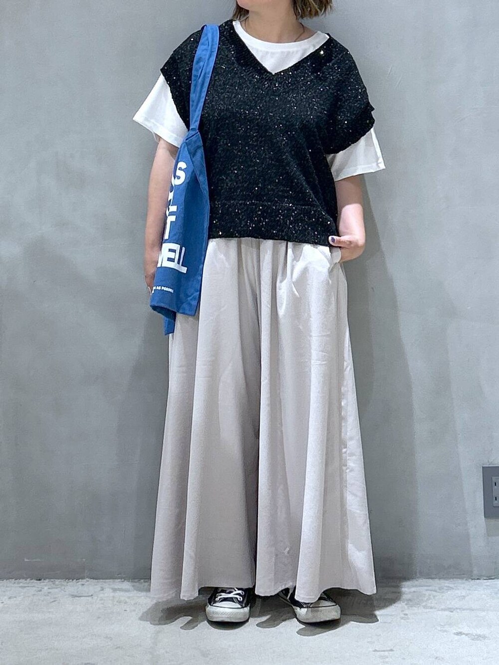 ブルー系のトートバッグ、ブラック系のベスト、グレー系のその他パンツを着用したレディースの夏コーディネートの6枚目の写真