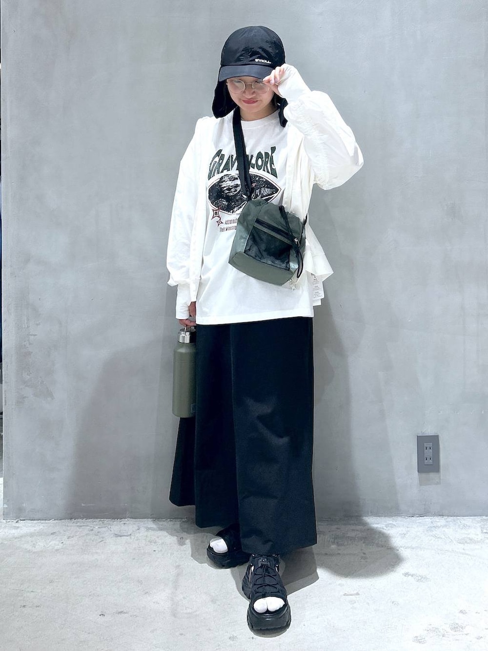 グリーン系のショルダーバッグ、ブラック系のスニーカー、ブラック系のスカートを着用したレディースの春コーディネートの6枚目の写真