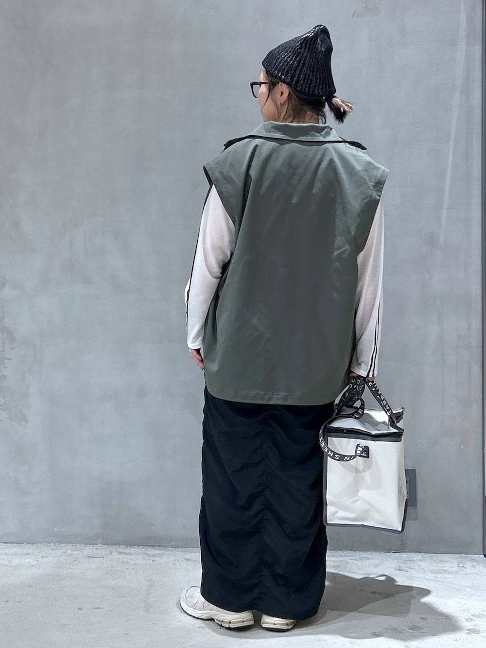 グリーン系のブルゾン、ホワイト系のTシャツ/カットソー、ブラック系のスカートを着用したレディースの秋コーディネートの2枚目の写真