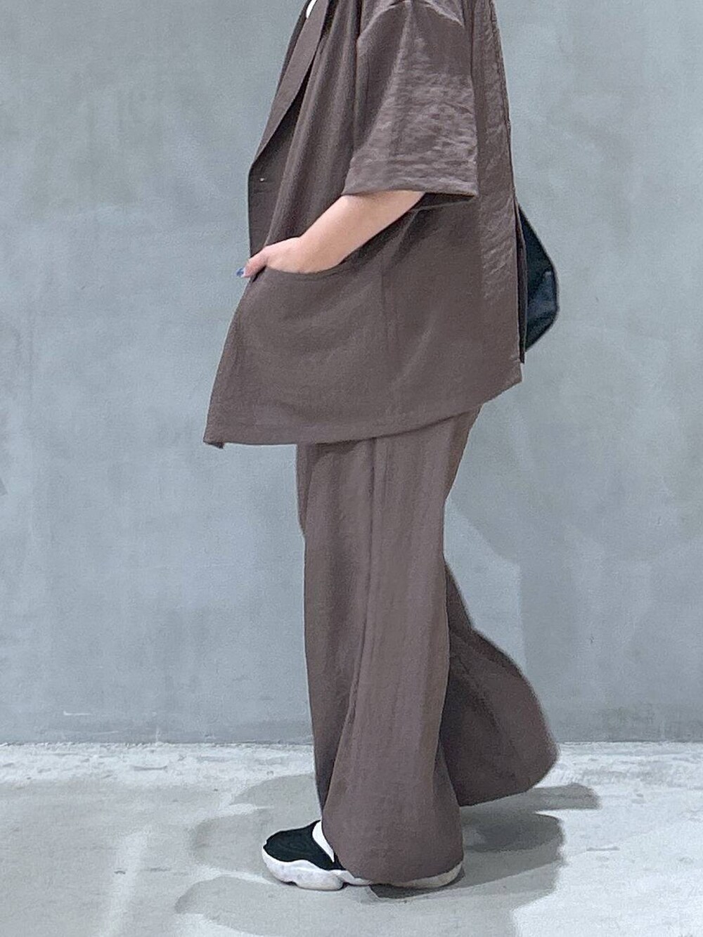 ブラック系のショルダーバッグ、ベージュ系のテーラードジャケット、ブラウン系のその他パンツを着用したレディースの夏コーディネートの4枚目の写真