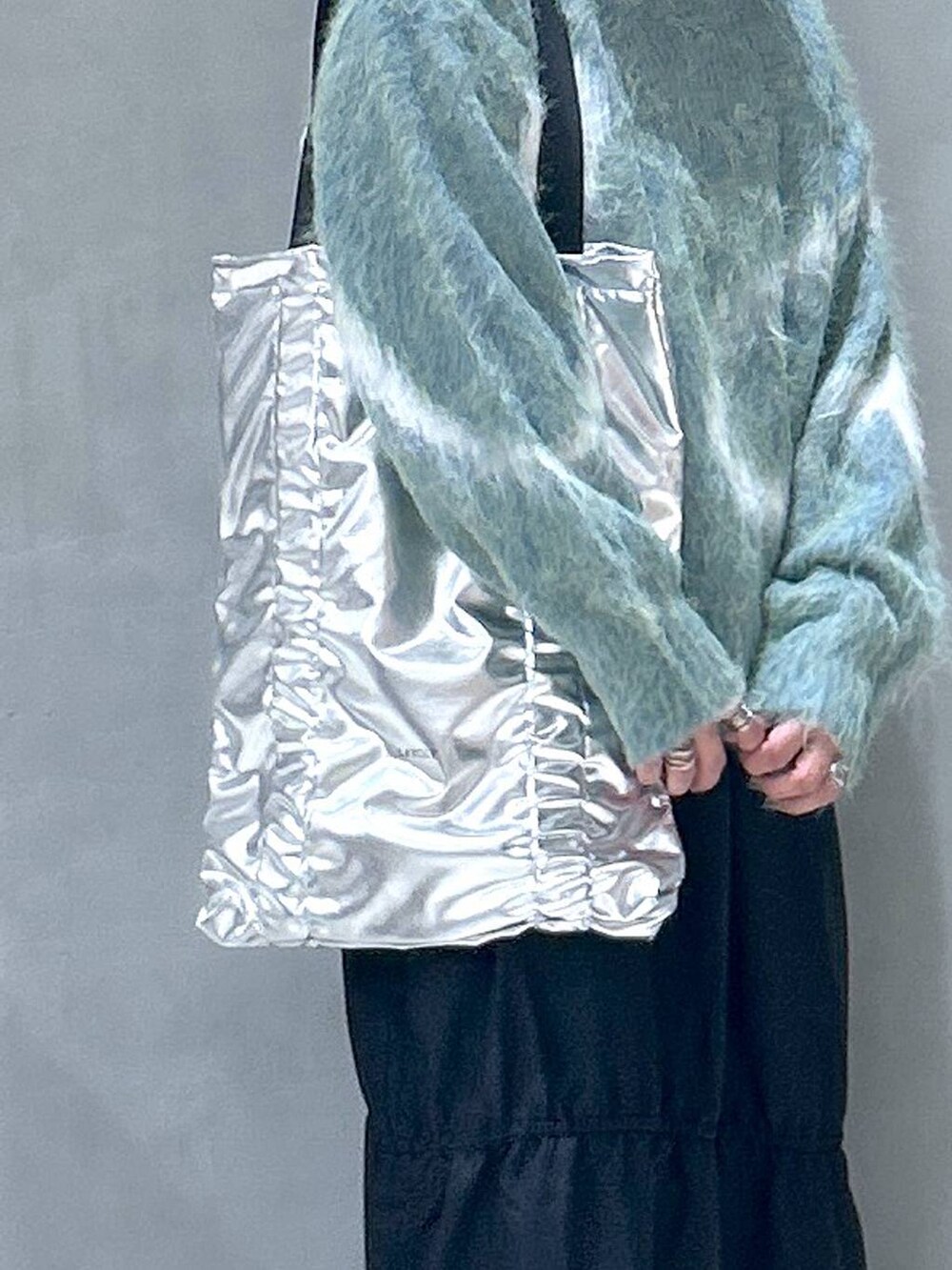 ホワイト系のスニーカー、グリーン系のニット/セーター、シルバー系のトートバッグを着用したレディースの秋コーディネートの4枚目の写真