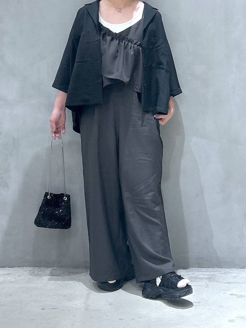 ブラック系のスニーカー、ホワイト系のタンクトップ、ブラック系のショルダーバッグを着用したレディースの春コーディネートの4枚目の写真