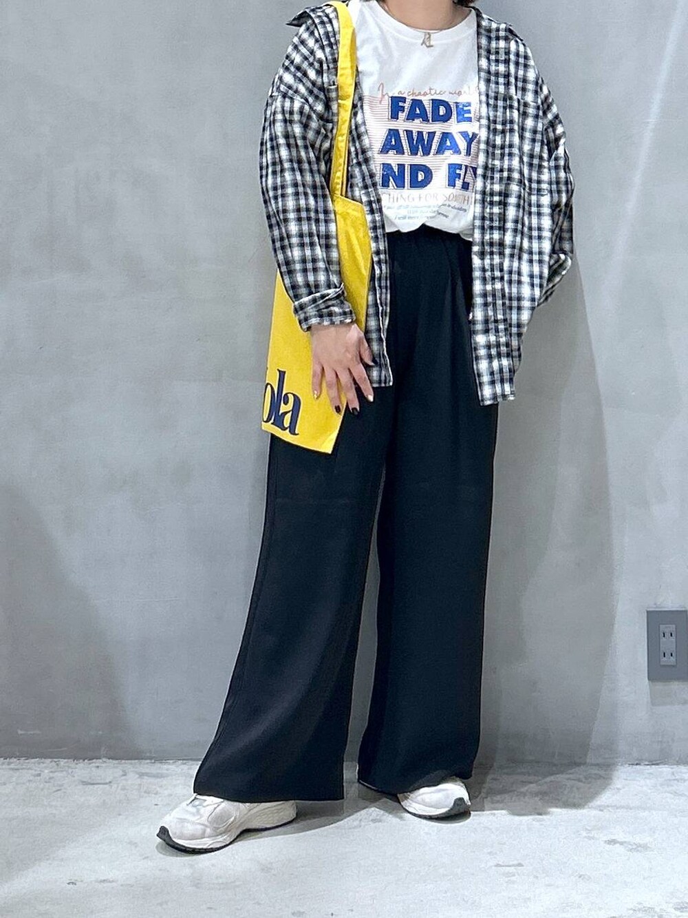 ブラック系のその他パンツ、ブラック系のシャツ/ブラウス、イエロー系のトートバッグを着用したレディースの春コーディネートの4枚目の写真