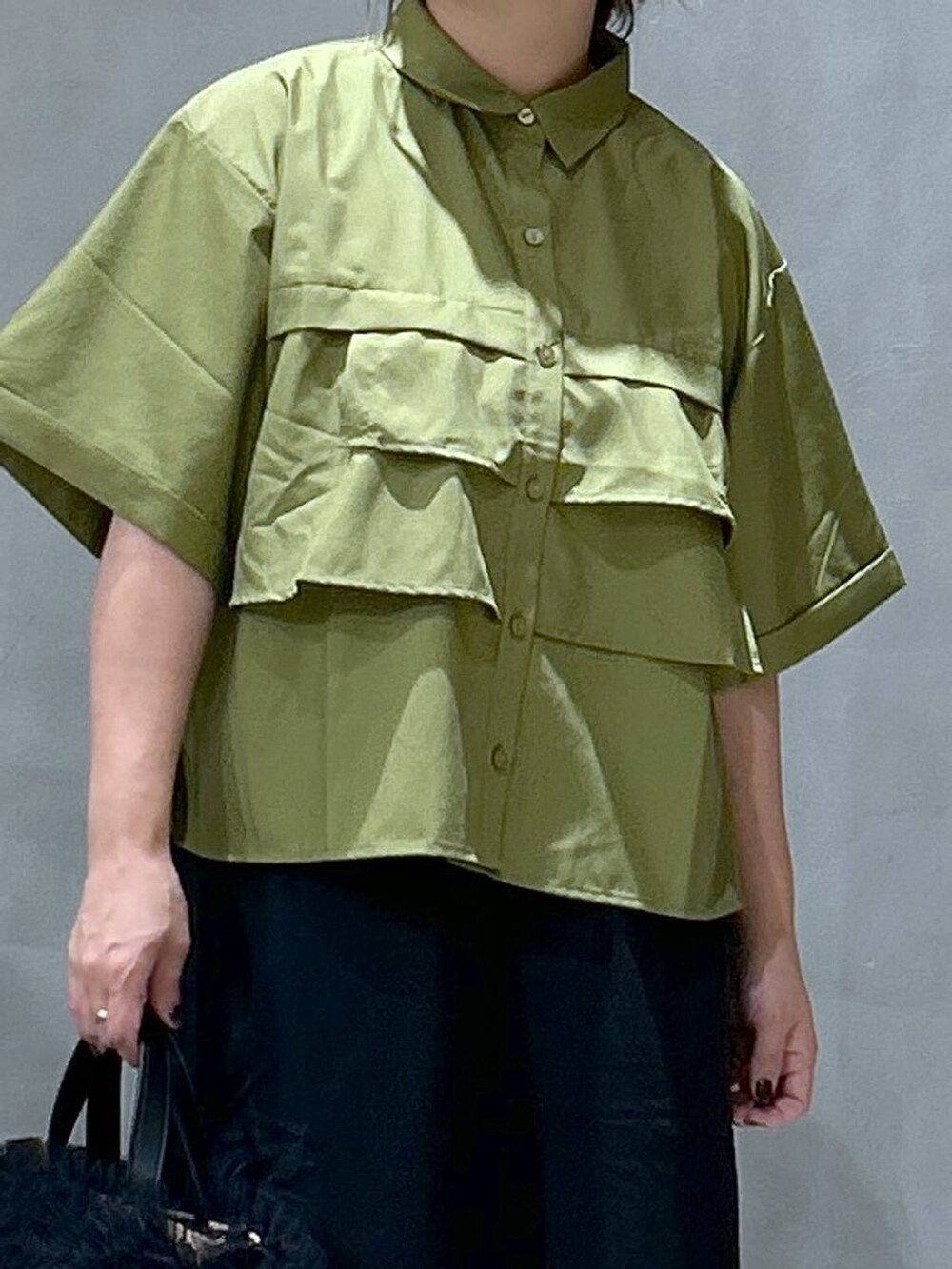 ブラック系のスカート、ベージュ系のショルダーバッグ、ブラック系のレインシューズを着用したレディースの夏コーディネートの3枚目の写真