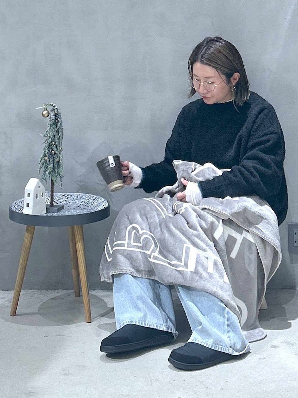 ブラック系のニット/セーター、ブルー系のデニムパンツ、ブラック系のスニーカーを着用したレディースの秋コーディネートの3枚目の写真