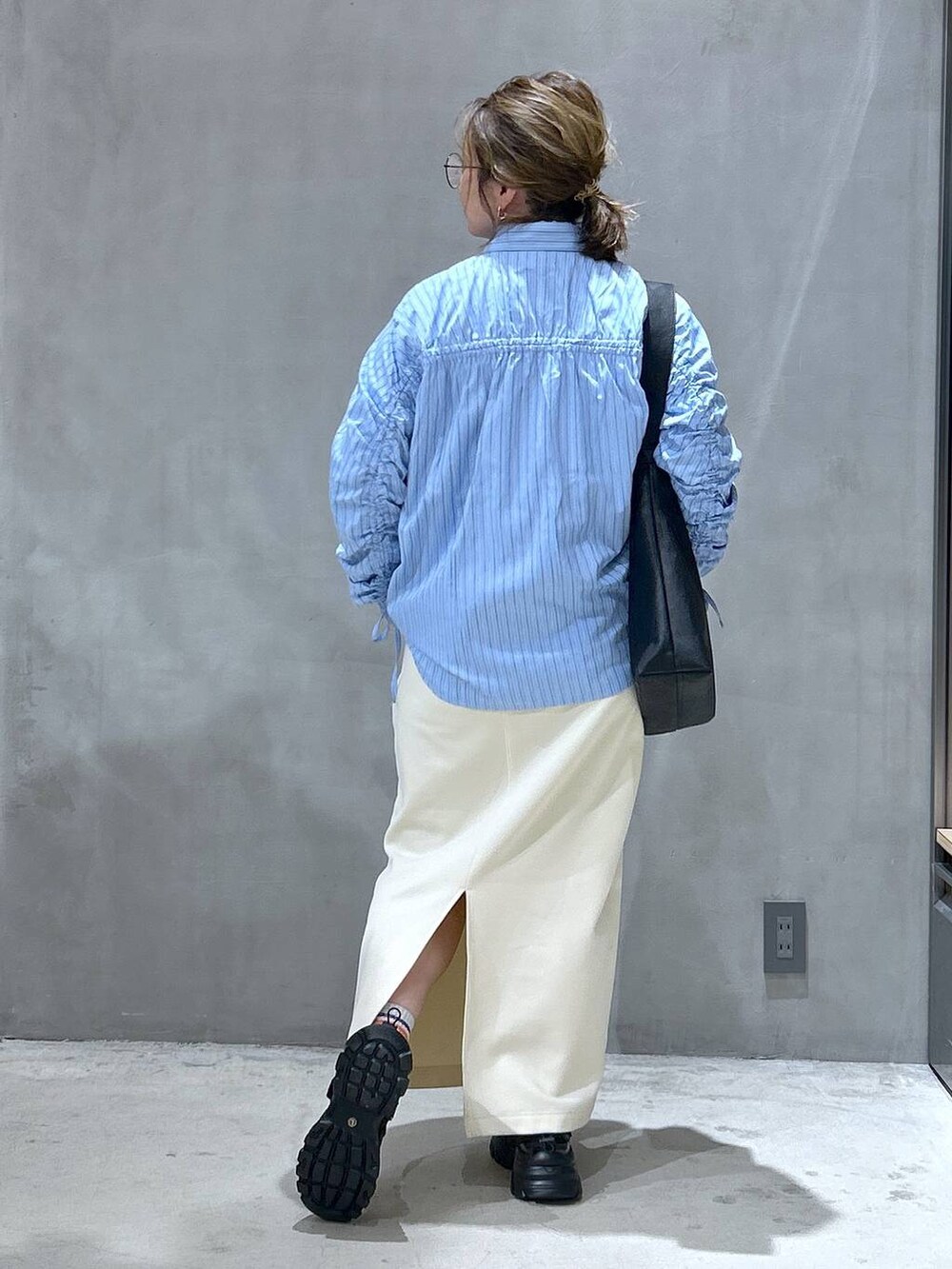 ホワイト系のスカート、ブラック系のスニーカー、ブラック系のショルダーバッグを着用したレディースの春コーディネートの2枚目の写真