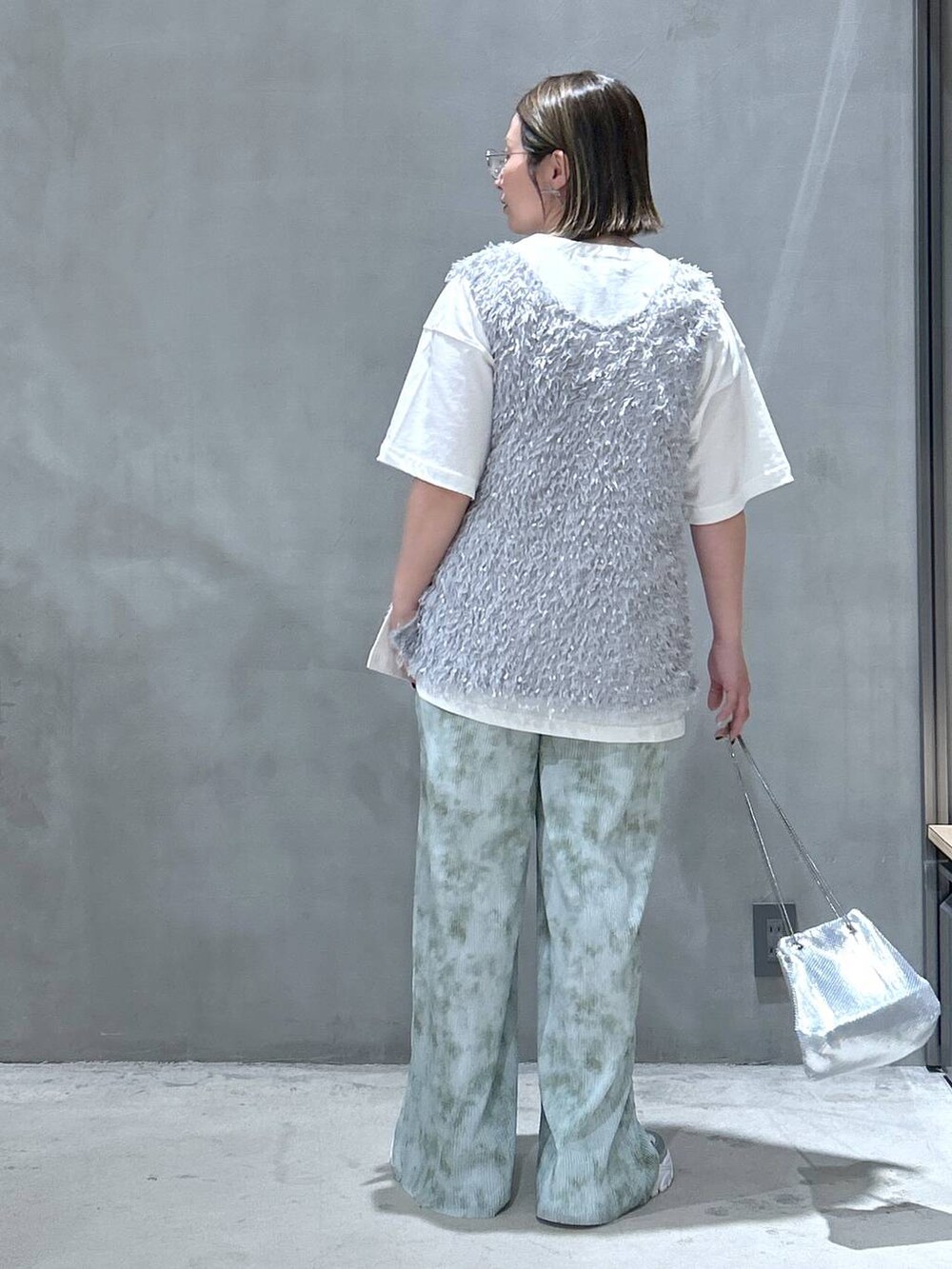 その他のショルダーバッグ、シルバー系のスニーカー、グレー系のベストを着用したレディースの春コーディネートの2枚目の写真