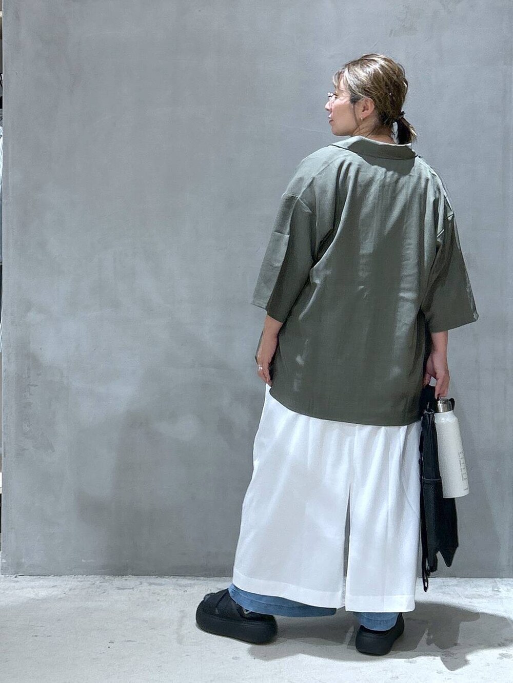 ブラック系のバックパック/リュック、グリーン系のシャツ/ブラウス、ブラック系のサンダルを着用したレディースの夏コーディネートの2枚目の写真