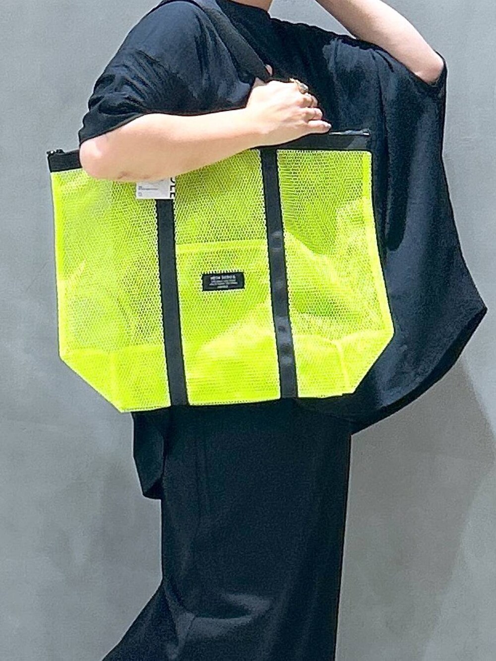 イエロー系のトートバッグ、ブラック系のスカート、ブラック系のサンダルを着用したレディースの夏コーディネートの4枚目の写真