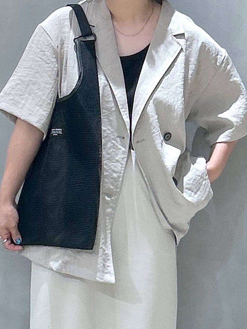 ブラック系のトートバッグ、ベージュ系のスカート、ベージュ系のテーラードジャケットを着用したレディースの夏コーディネートの3枚目の写真