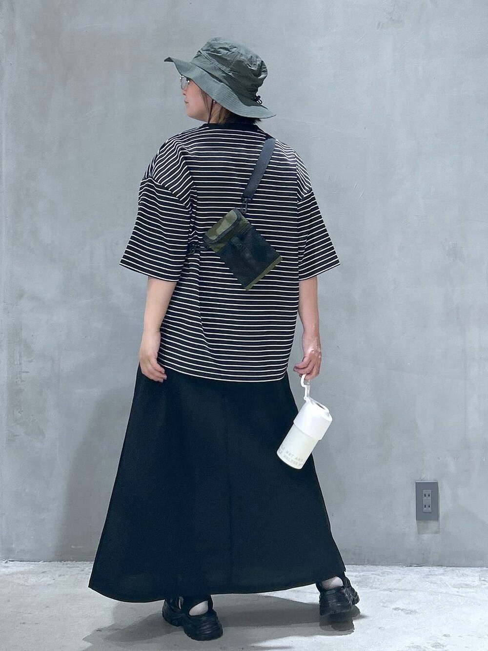 グリーン系のショルダーバッグ、ブラック系のスニーカー、ブラック系のスカートを着用したレディースの春コーディネートの2枚目の写真