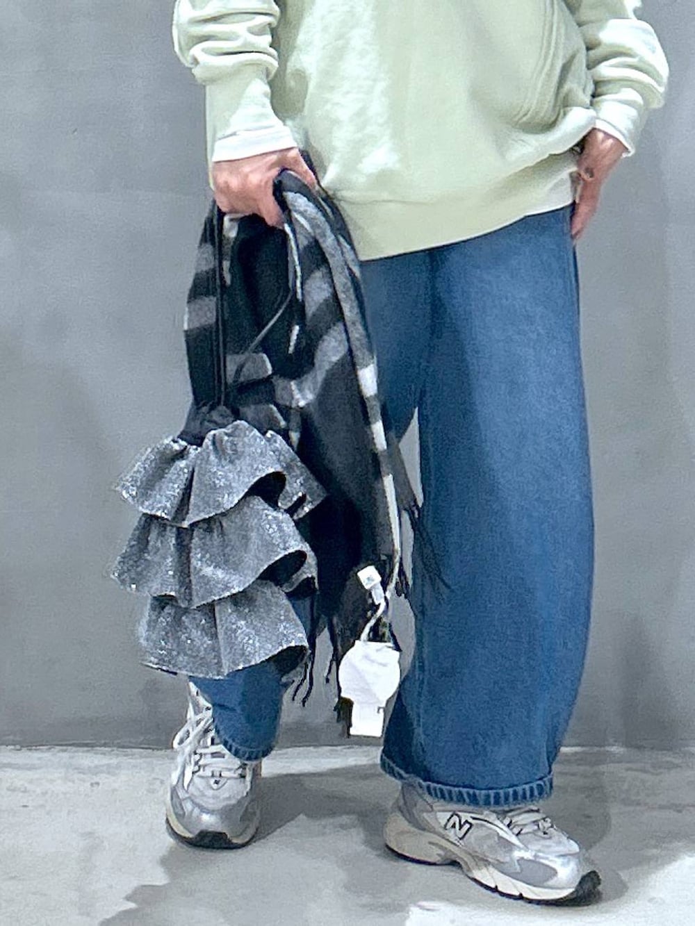 ブルー系のデニムパンツ、シルバー系のショルダーバッグ、グリーン系のスウェットを着用したレディースの冬コーディネートの3枚目の写真
