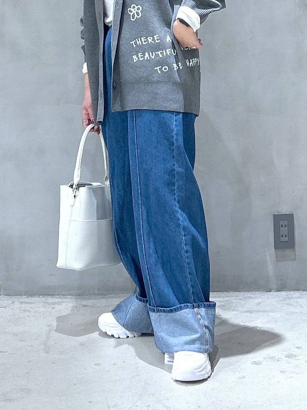 ホワイト系のスニーカー、ブルー系のデニムパンツ、ホワイト系のショルダーバッグを着用したレディースの秋コーディネートの3枚目の写真