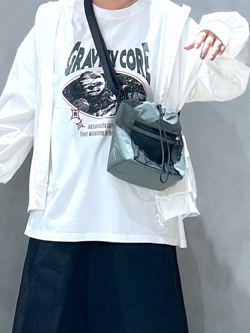 グリーン系のショルダーバッグ、ブラック系のスニーカー、ブラック系のスカートを着用したレディースの春コーディネートの3枚目の写真