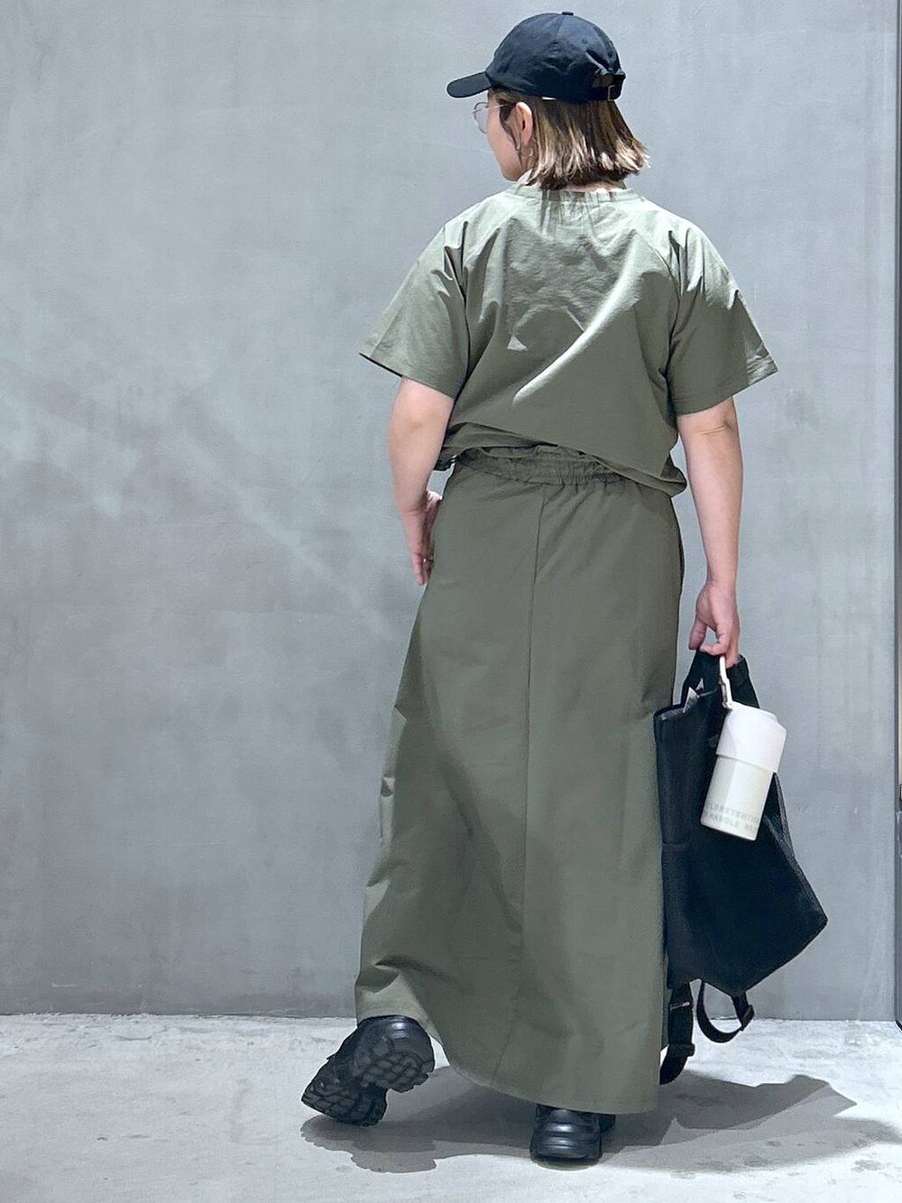 ブラック系のバックパック/リュック、ブラック系のスニーカー、グリーン系のTシャツ/カットソーを着用したレディースの春コーディネートの2枚目の写真