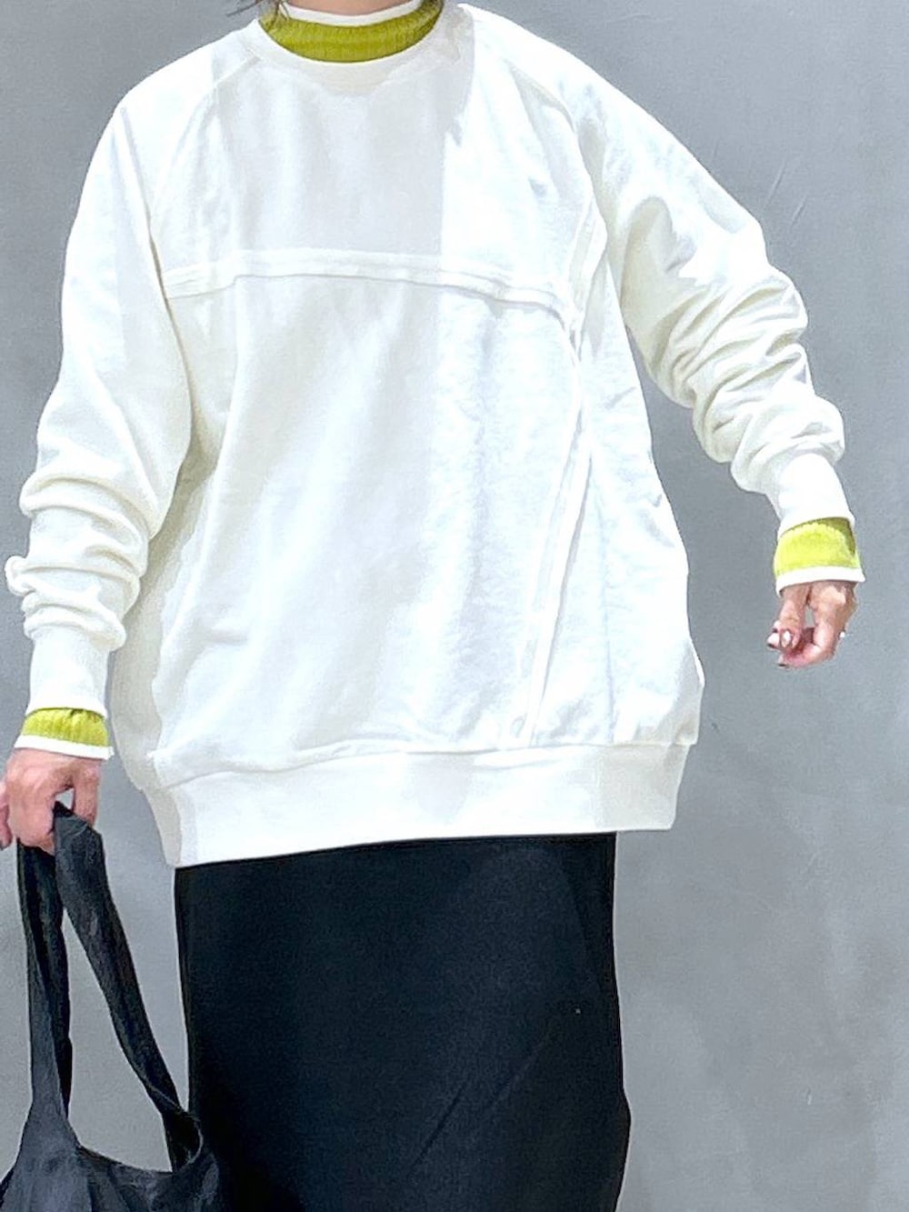 グリーン系のニット/セーター、ブラック系のブーツ、ブラック系のエコバッグ/サブバッグを着用したレディースの冬コーディネートの3枚目の写真