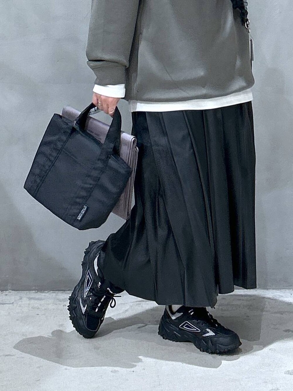 グレー系のスニーカー、ブラック系のスカート、グレー系のアウトドアグッズを着用したレディースの秋コーディネートの4枚目の写真