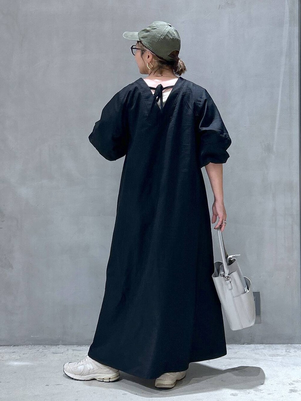 グレー系のショルダーバッグ、ブラック系のワンピース、グリーン系のキャップを着用したレディースの夏コーディネートの2枚目の写真