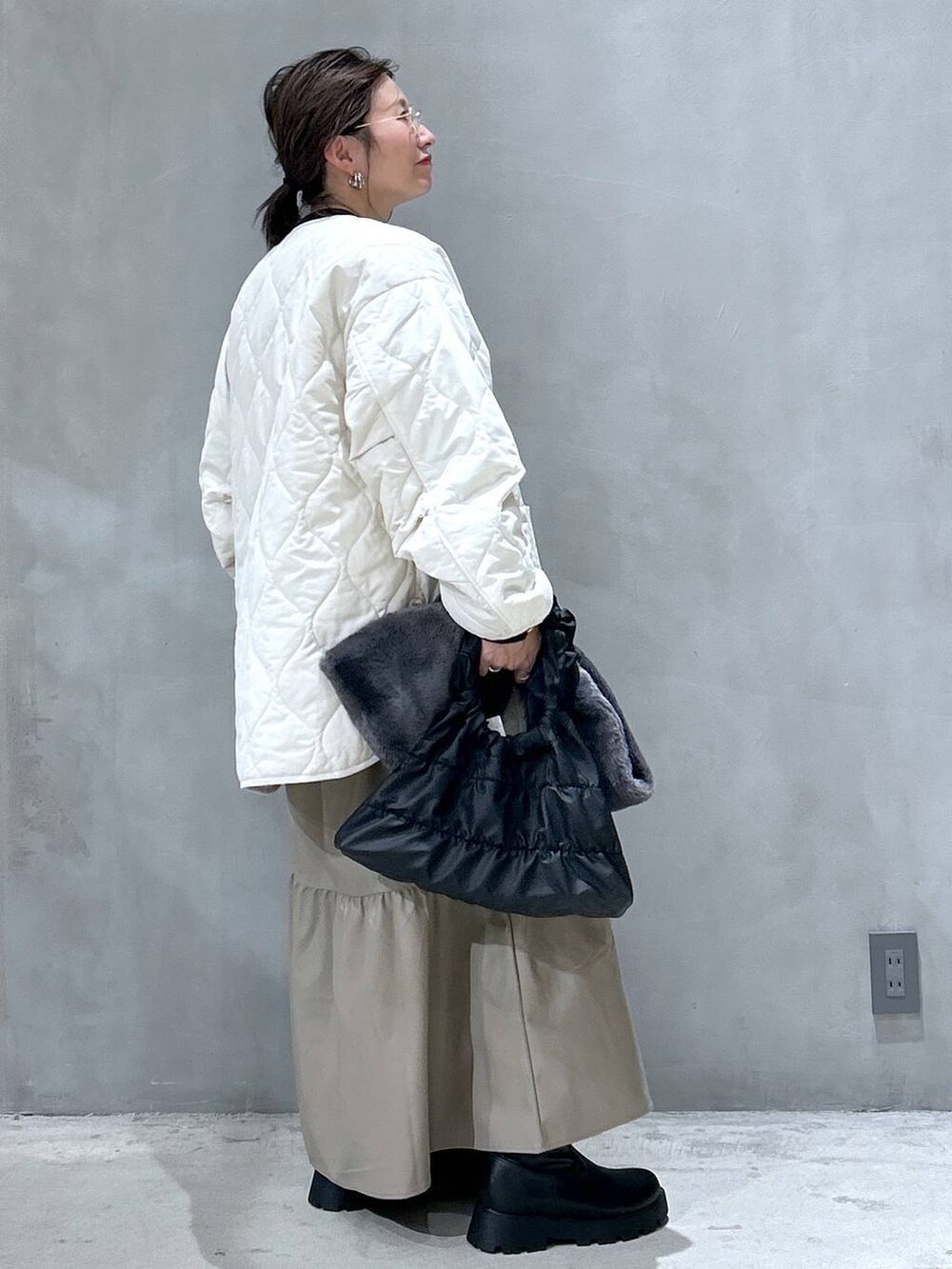 ブラック系のニット/セーター、ベージュ系のブルゾン、ブラック系のブーツを着用したレディースの秋コーディネートの2枚目の写真