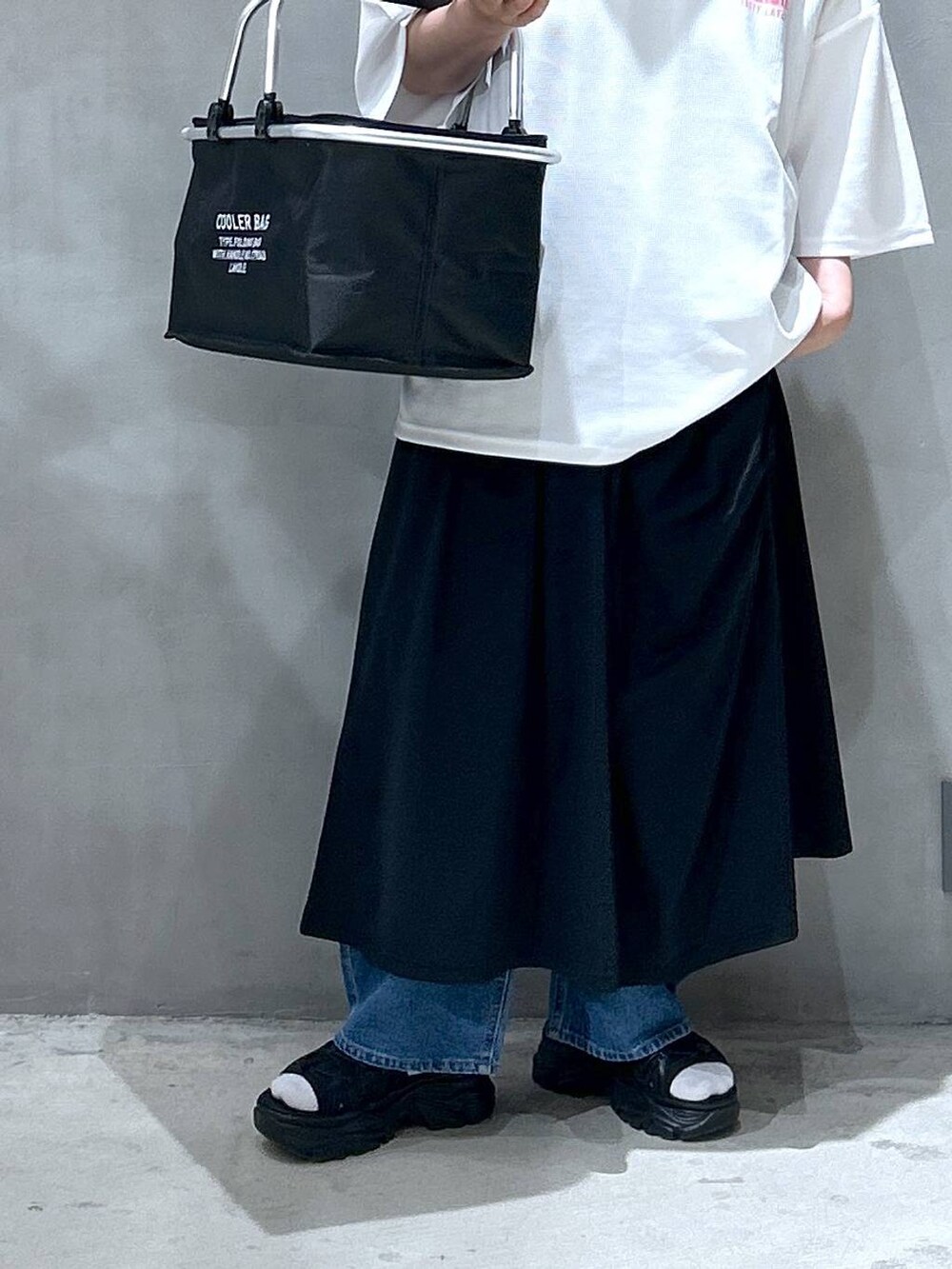 ブルー系のデニムパンツ、ブラック系のスニーカー、ブラック系のワンピースを着用したレディースの春コーディネートの5枚目の写真