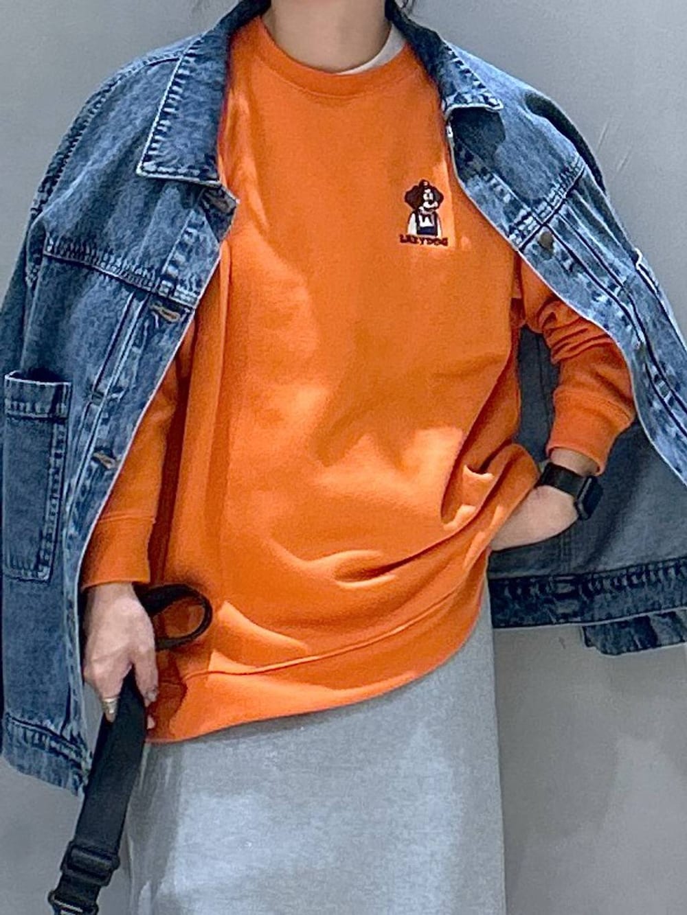 グレー系のスニーカー、ブラック系のショルダーバッグ、ブルー系のデニムジャケットを着用したレディースの秋コーディネートの3枚目の写真