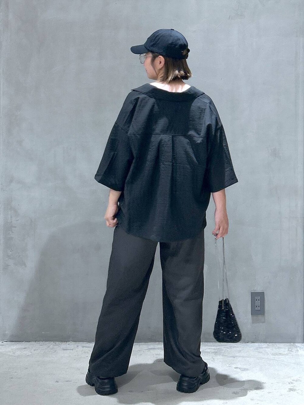 ブラック系のスニーカー、ホワイト系のタンクトップ、ブラック系のショルダーバッグを着用したレディースの春コーディネートの2枚目の写真