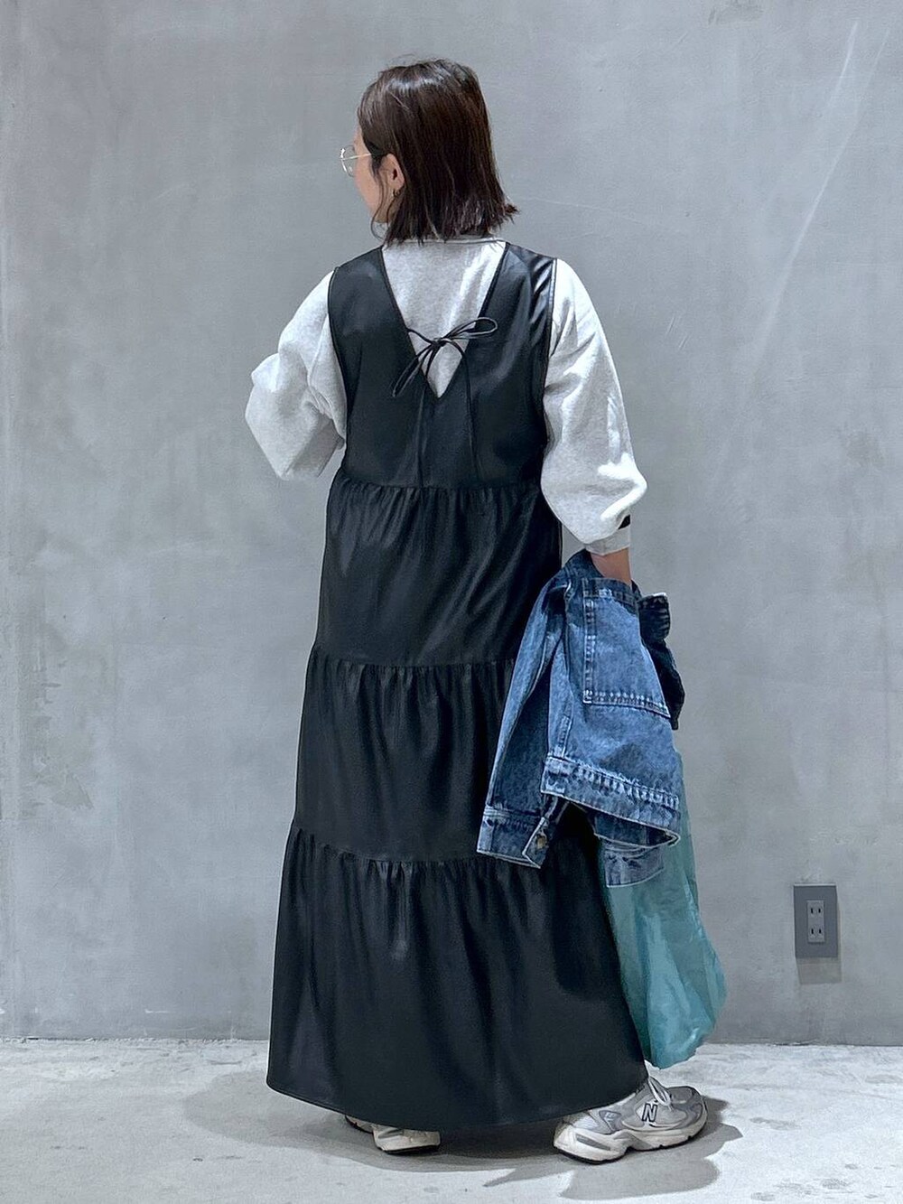 グレー系のスニーカー、ブラック系のワンピース、ブルー系のデニムジャケットを着用したレディースの秋コーディネートの2枚目の写真