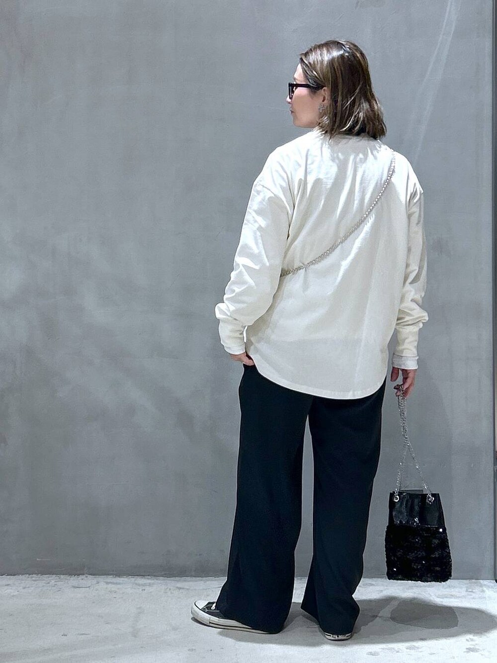 ブラック系のその他パンツ、ブラック系のショルダーバッグ、ベージュ系のTシャツ/カットソーを着用したレディースの冬コーディネートの2枚目の写真