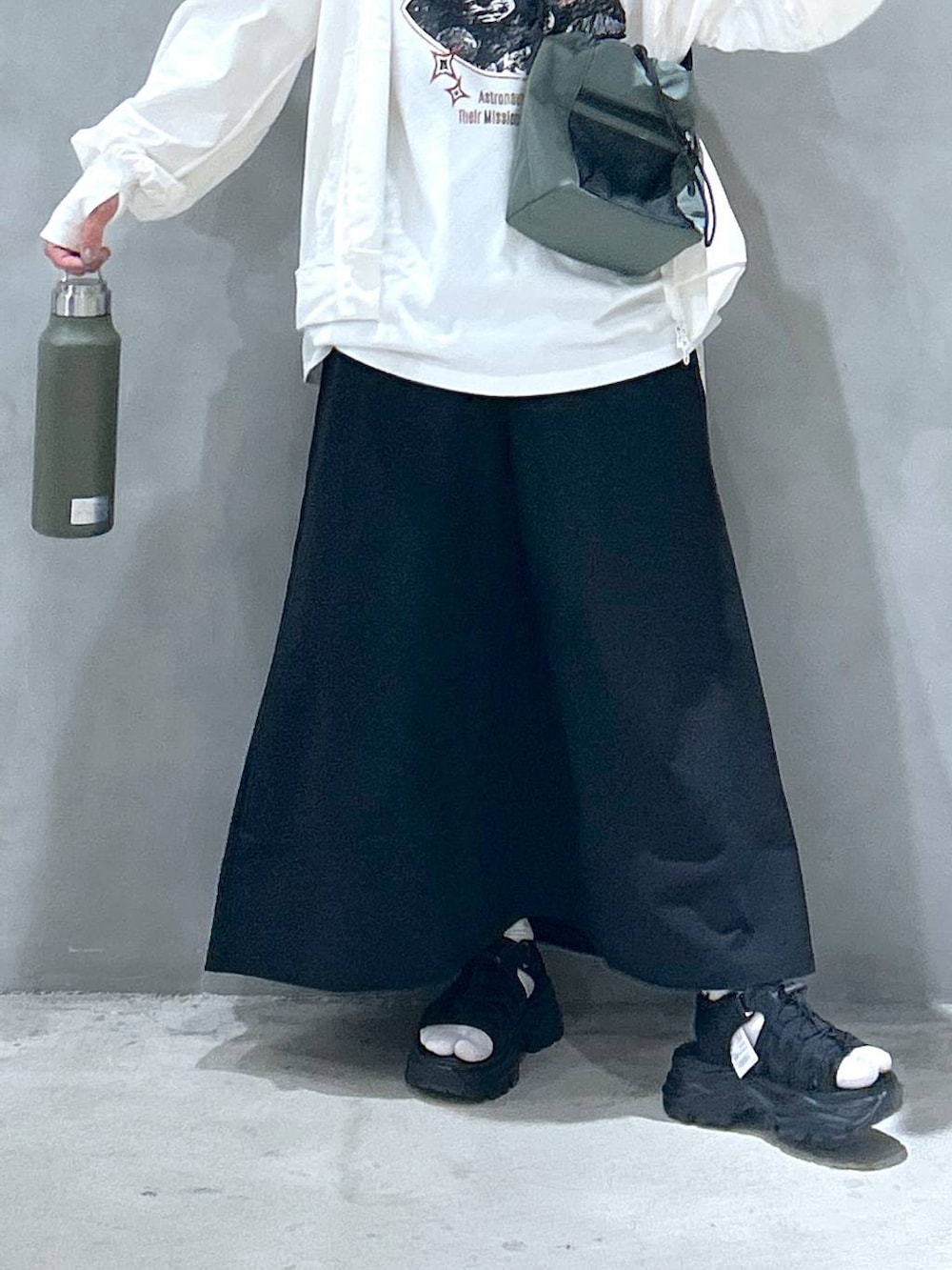 グリーン系のショルダーバッグ、ブラック系のスニーカー、ブラック系のスカートを着用したレディースの春コーディネートの4枚目の写真