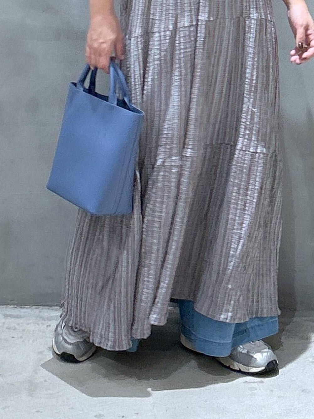 グレー系のワンピース、ブルー系のデニムパンツ、ブルー系のショルダーバッグを着用したレディースの夏コーディネートの6枚目の写真