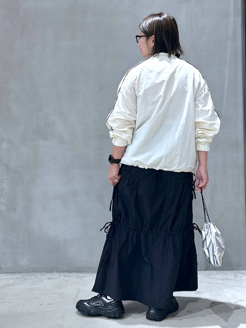 グレー系のスニーカー、ベージュ系のブルゾン、ブラック系のスカートを着用したレディースの秋コーディネートの2枚目の写真