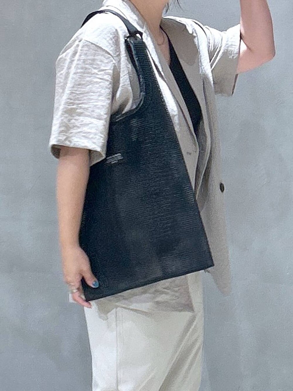 ブラック系のトートバッグ、ベージュ系のスカート、ベージュ系のテーラードジャケットを着用したレディースの夏コーディネートの5枚目の写真