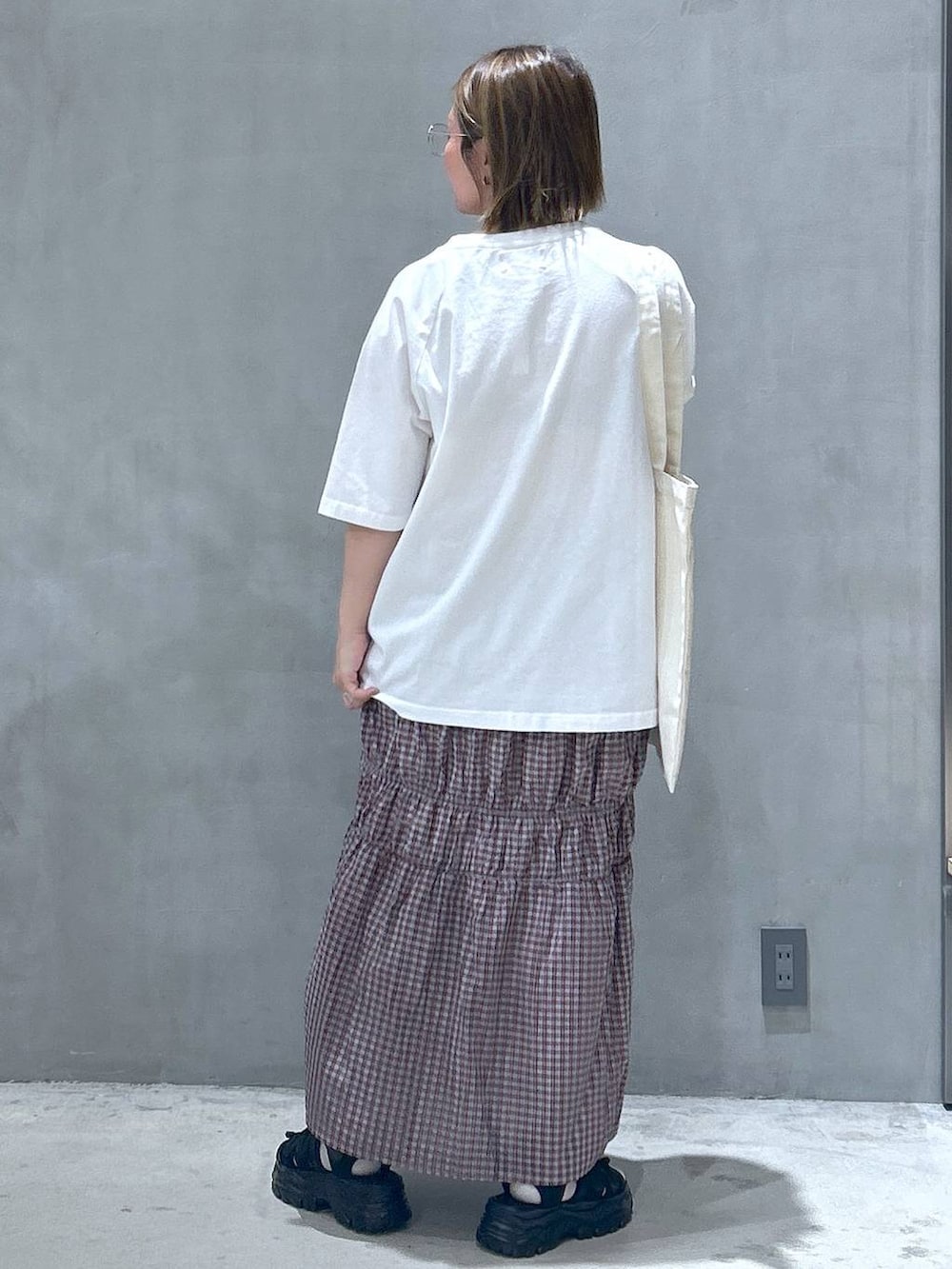 ブラック系のスニーカー、オレンジ系のスカート、ホワイト系のTシャツ/カットソーを着用したレディースの春コーディネートの2枚目の写真