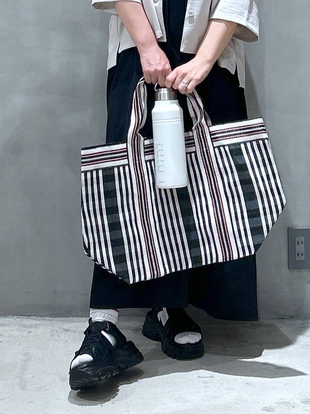 ブラック系のスニーカー、ブラック系のトートバッグ、ブラック系のワンピースを着用したレディースの春コーディネートの4枚目の写真