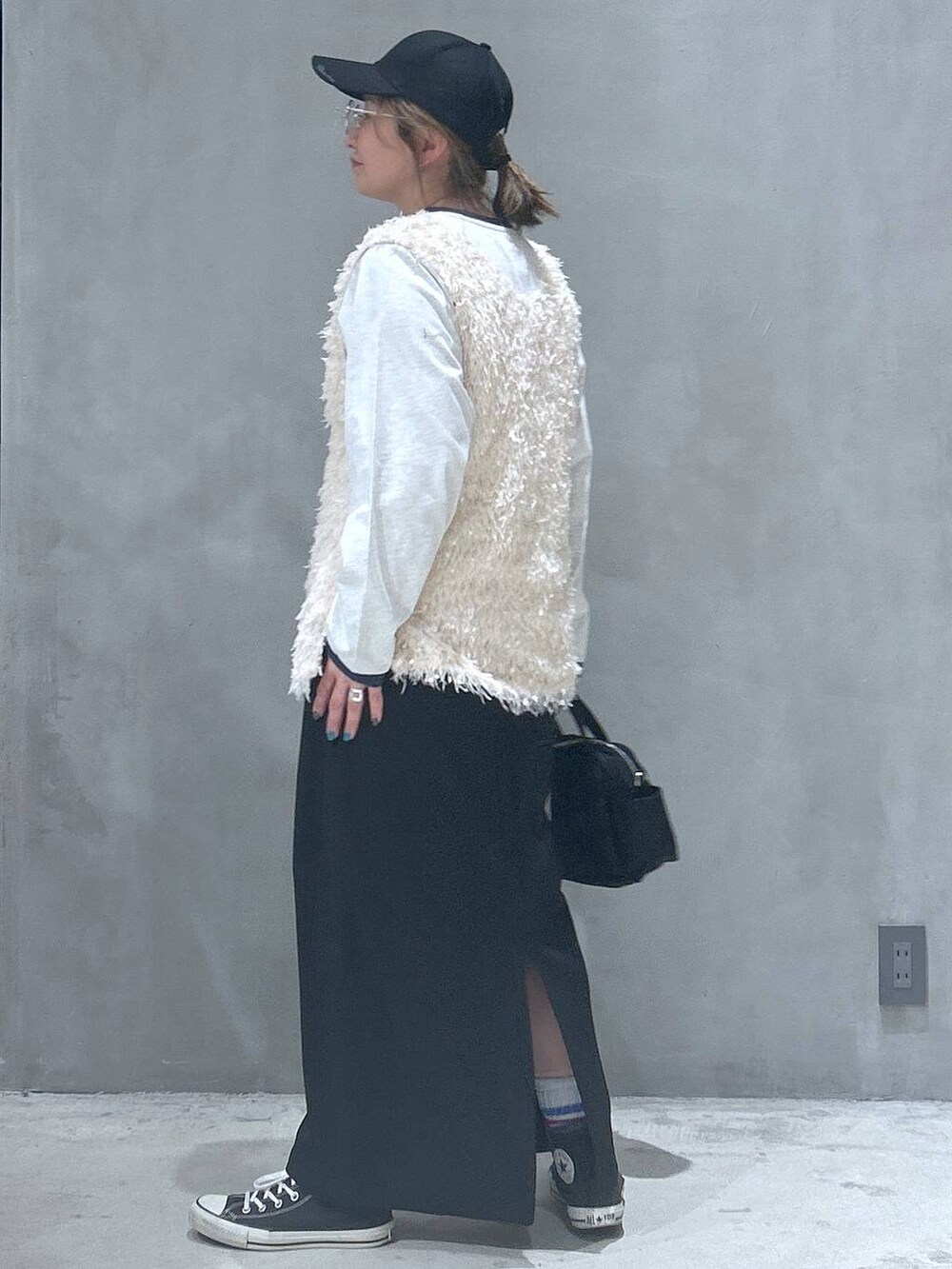 ブラック系のスカート、ホワイト系のベスト、ベージュ系のTシャツ/カットソーを着用したレディースの春コーディネートの4枚目の写真