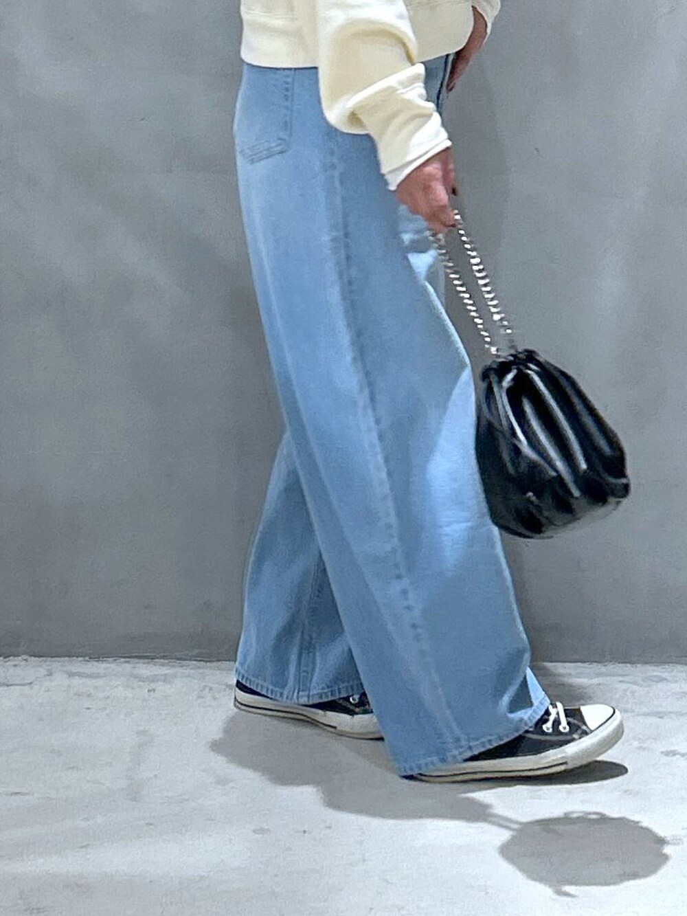 ブルー系のデニムパンツ、ベージュ系のTシャツ/カットソー、ブラック系のショルダーバッグを着用したレディースの冬コーディネートの6枚目の写真