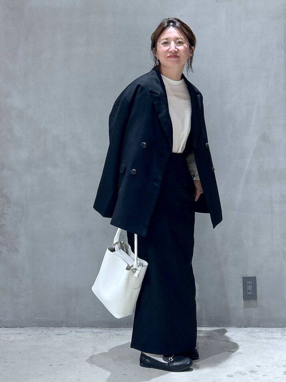 ブラック系のテーラードジャケット、ホワイト系のショルダーバッグ、ブラック系のローファーを着用したレディースの秋コーディネートの7枚目の写真