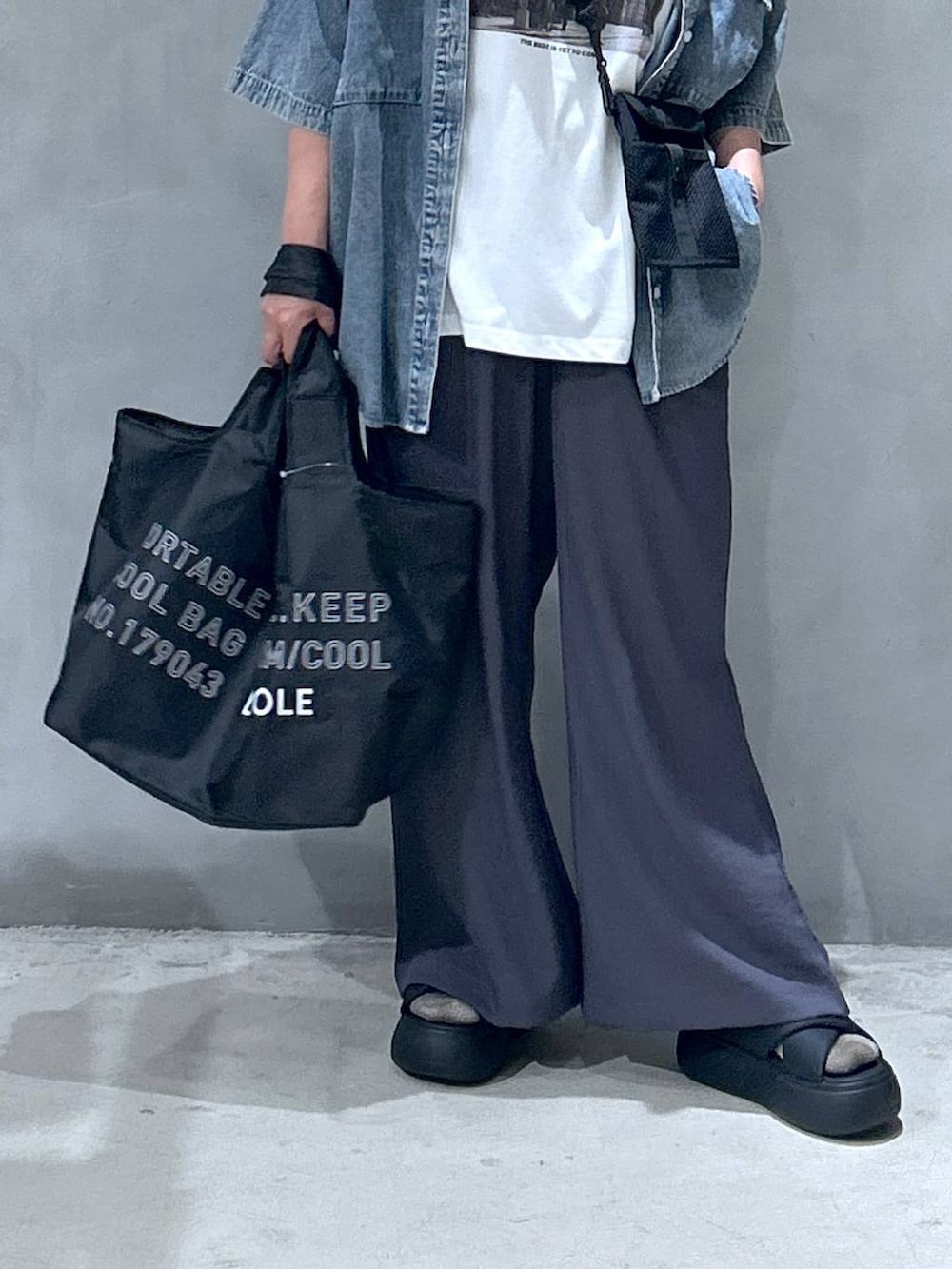 ブラック系のショルダーバッグ、ブラック系のサンダル、ブルー系のシャツ/ブラウスを着用したレディースの夏コーディネートの3枚目の写真